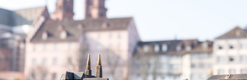 Im Vordergrund ein Miniaturmodel des Münster in Basel. Im Hintergrund liegt das tatsächliche Gebäude in der Ferne.