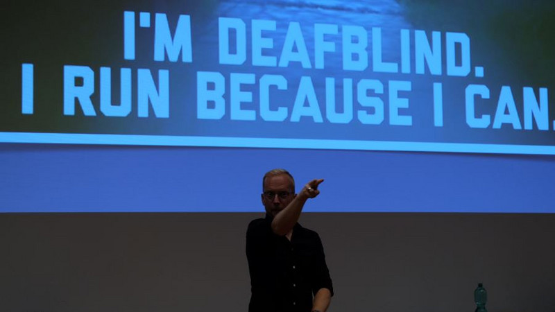 James Clarke mit Präsentationshintergrund "I´m deafblind. I run because I can."