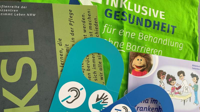 Praxishandbuch, Türanhänger, Tasche "Inklusive Gesundheit und Buch "Nina im Krankenhaus" sind dargestellt.