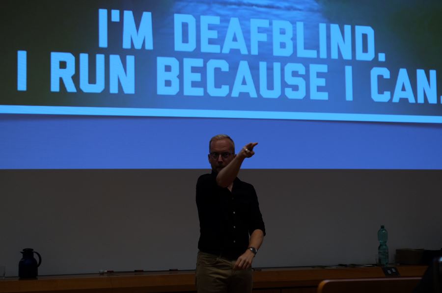 James Clarke mit Präsentationshintergrund "I´m deafblind. I run because I can."