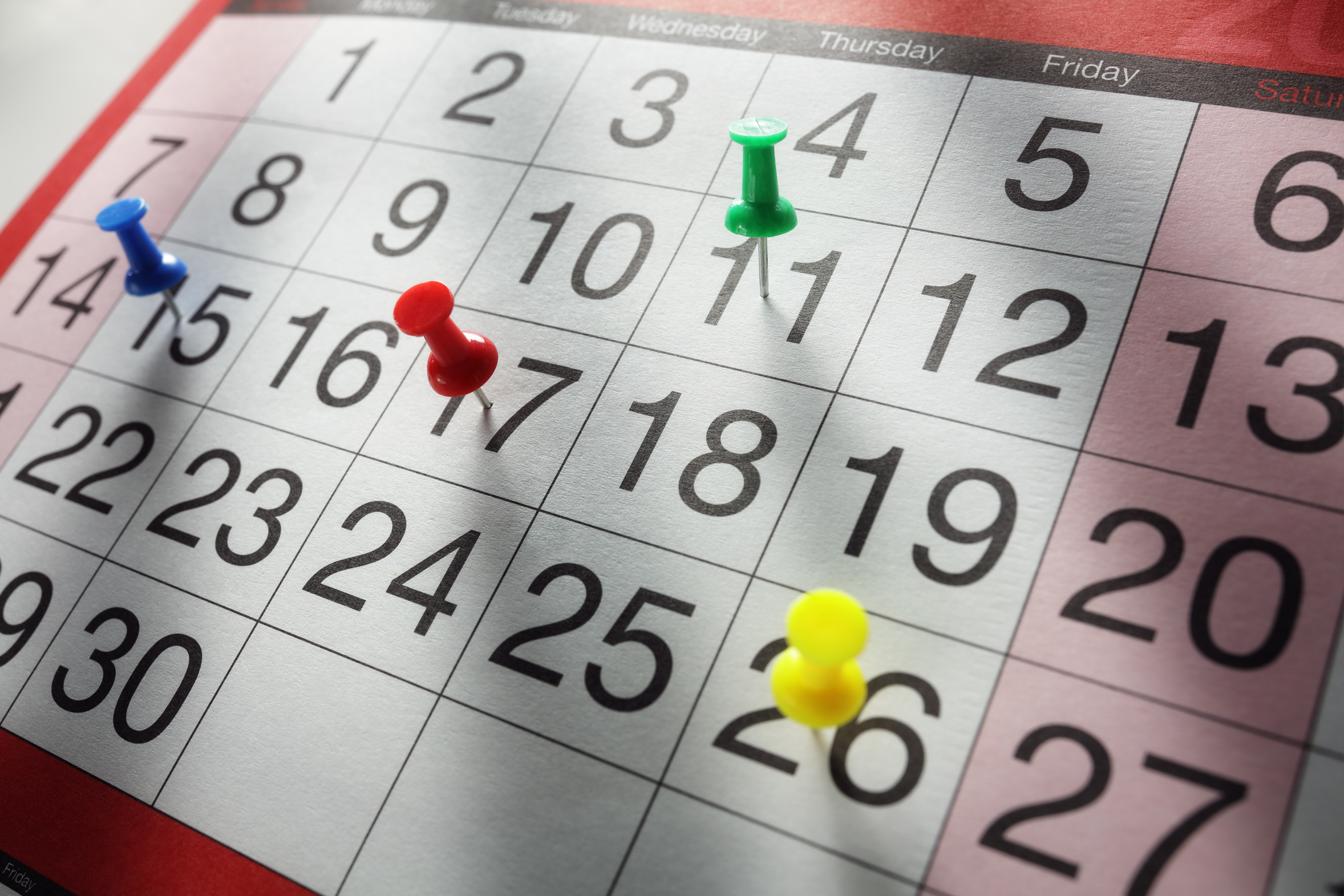 Kalenderblatt mit Pinnadeln auf verschiedenen Tagen
