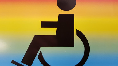 Das Bild zeigt das Zeichen für RollstuhlfahererIn auf einem Regenbogen-Hintergrund.