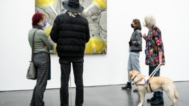 Mehrere Personen und ein Blindenführhund stehen vor einem Bild in der Kunsthalle.