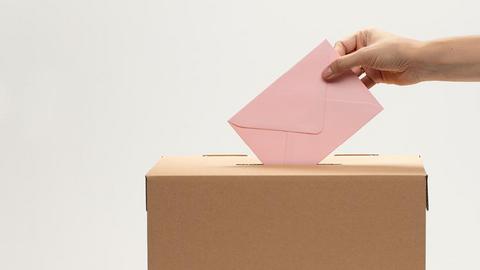 Mann wirft Stimmzettel in die Wahlurne