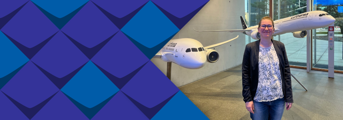 Melanie Wegerhoff  steht vor zwei großen Lufthansa-Flugzeugmodellen.  