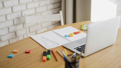 Laptop, Block, Markierungsstifte und Übungssteine mit Zahlen auf dem Schreibtisch
