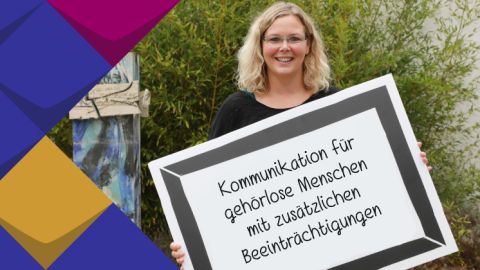 Foto von Frau Ender. Sie hält ein Schild, auf dem der Name der Veranstaltung steht.