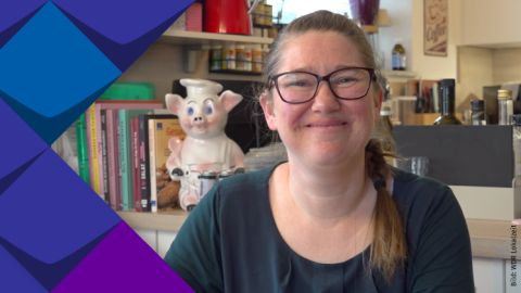 Melanie Wegerhoff erzählt über die Taubblindheit. Im Hintergrund ist Melanie Wegerhoff zu sehen und sie befindet sich im Raum.