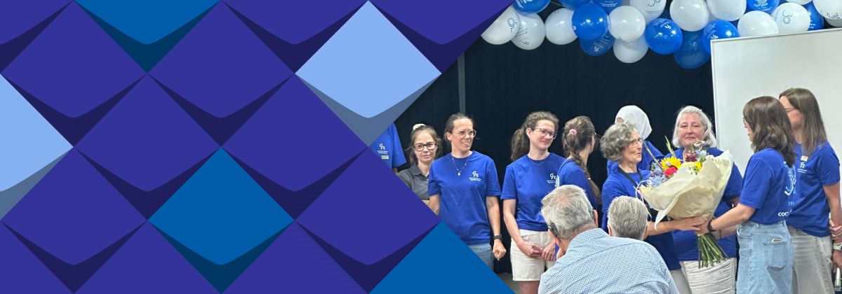Frau Bagus bekommt die Blummen für Ihre Arbeit. Mitarbeiter*innen vom Team stehen und gratulieren Ihr erfolgreiche Zusammenarbeit.