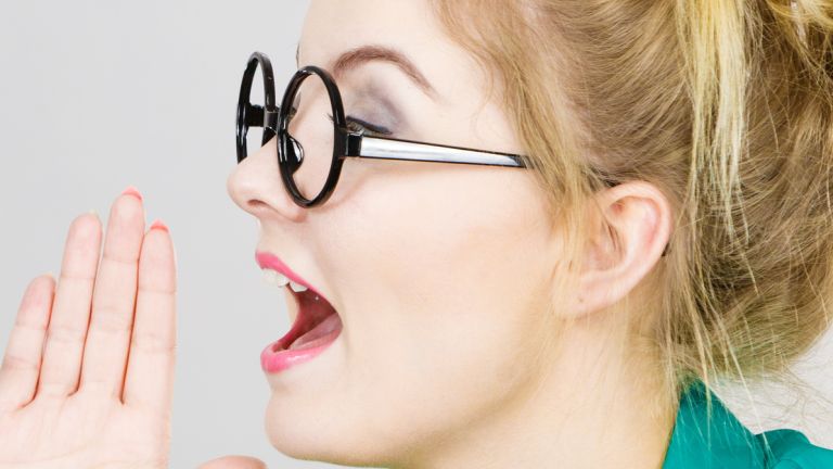 Eine Frau ist seitlich zu sehen. Sie hält die flache Hand neben den geöffenten Mund