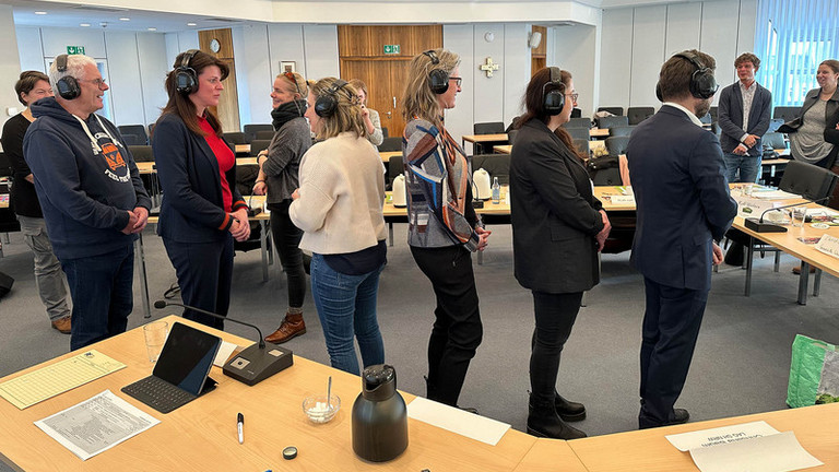 Teilnehmenden stehen in einer Schlange: Kristin Reker moderiert die Übung Stille Post 